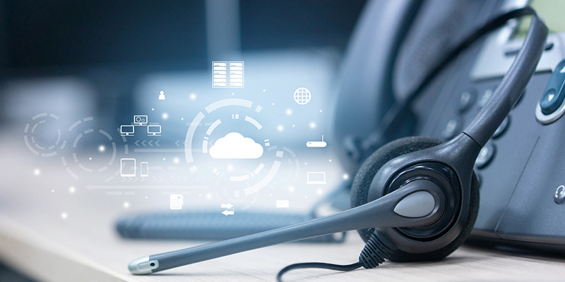Image of a headset and landline office phone on a desk with white cloud device icons