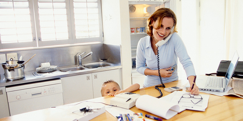 Image of a mother at home talking on the phone in the kitchen with her child